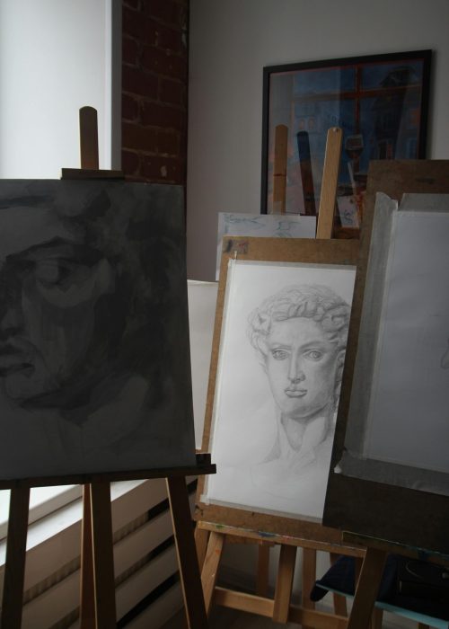 pexels-photo-12081833-12081833 A serene art studio with classical sketches displayed on easels by a window.